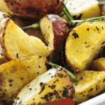 A white platter of roasted potatoes seasoned with herbs and rosemary used for post called Are Potatoes Healthy or Do They Warrant Caution?