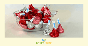 clear candy dish filled with Hershey's Kisses wrapped in silver, red, and rose colored foil